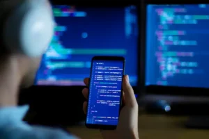 Programmer reviewing programming code on computer and phone