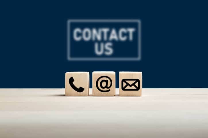 Wooden cubes on a blue background featuring contact us icons for companies migrating to the cloud.