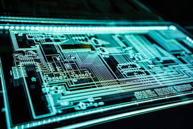 Close-up of a glowing digital circuit board with intricate lines and components, illuminated in blue and green tones.